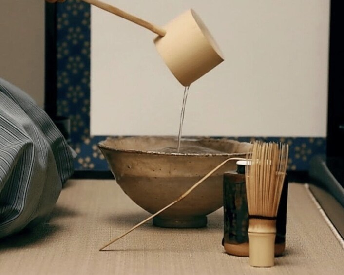 A wooden whisk, a bowl, and a pouring jug on a table. 3