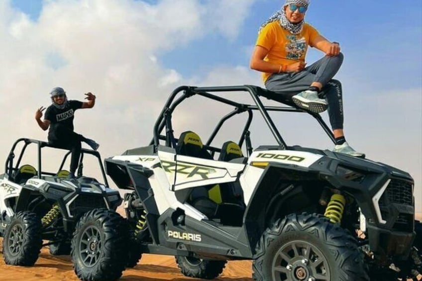 Deux véhicules tout-terrain Polaris, équipés de gros pneus, avec un paysage désertique en arrière-plan. 2