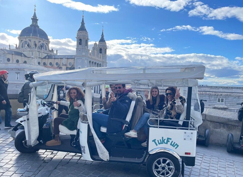 A group of people on a TukFun electric vehicle near a historic building with domes and towers. 2