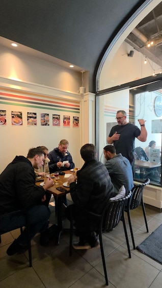 A group of people dining at a restaurant with a modern interior, including striped wall decor and a large window. 1
