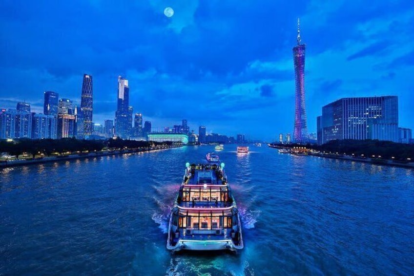 A river with a boat in the foreground, a city skyline with illuminated buildings in the background, and a prominent tower on the right. 1