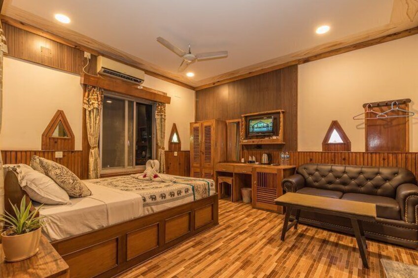 A cozy room with a bed, a sofa, a TV, and wooden paneling. 4