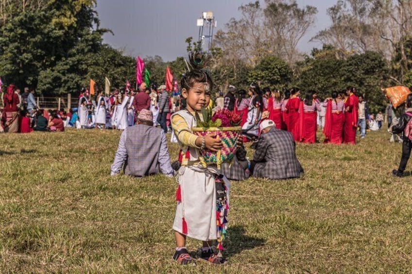 A person in traditional attire holding a colorful item, with a crowd in the background. 2