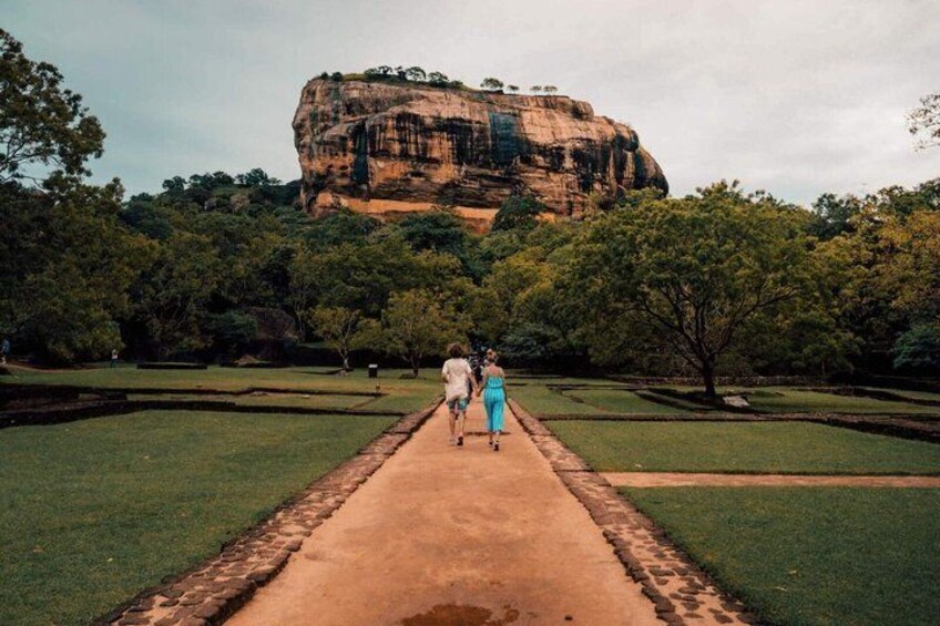 A pathway leading to a large rock formation surrounded by trees. 2