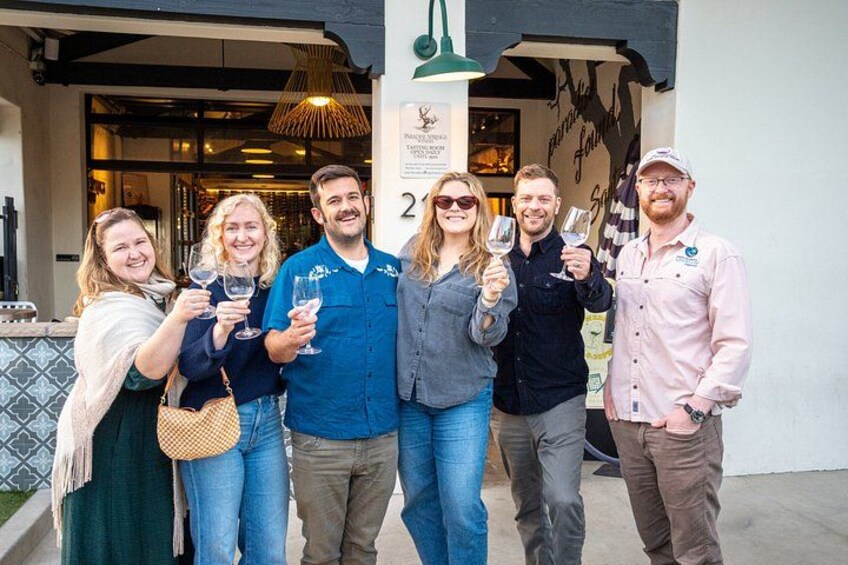 Un grupo de personas sosteniendo copas de vino frente a un edificio con un letrero que dice 'POUR SOIR'. 1