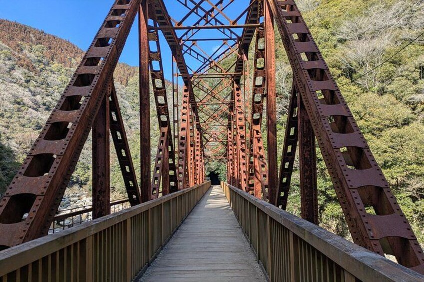 A metal bridge with a wooden walkway, surrounded by a mountainous landscape. 1