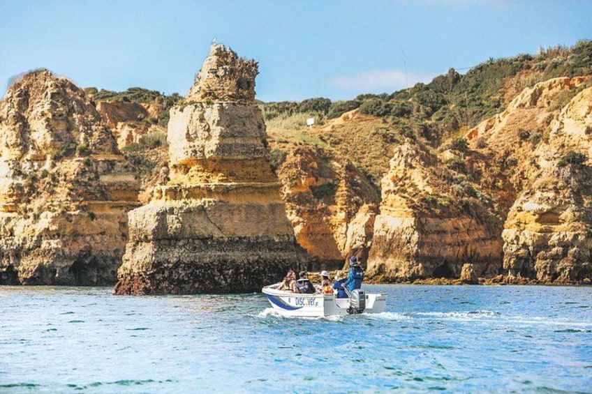 A boat on calm waters with rocky cliffs in the background. 1