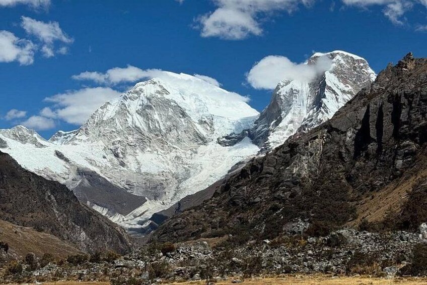 A snow-capped mountain range with rocky outcrops and a clear blue sky. 3