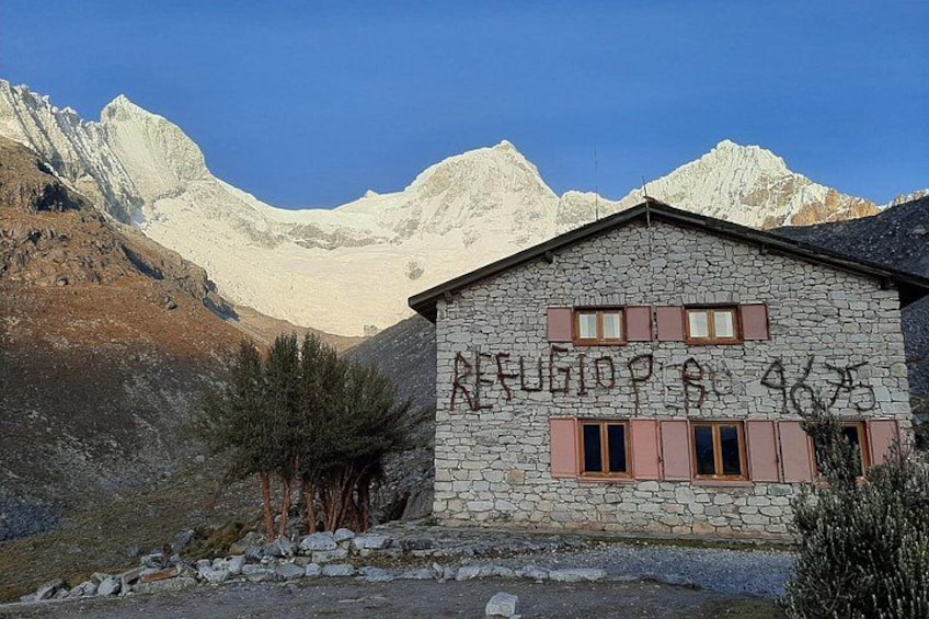 A stone building with graffiti, surrounded by mountains and sparse vegetation. 5