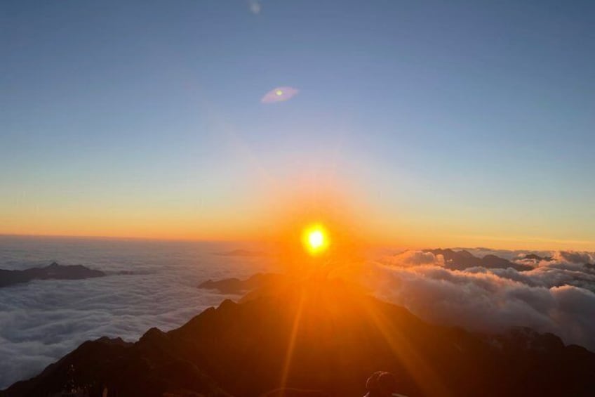 A sunrise over a mountain range with clouds below. 1