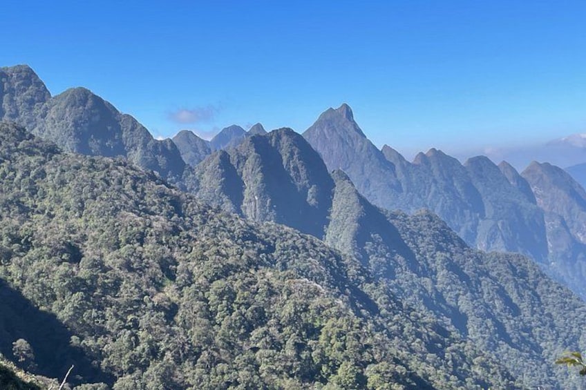 A mountain range with dense forest coverage and rugged peaks. 5
