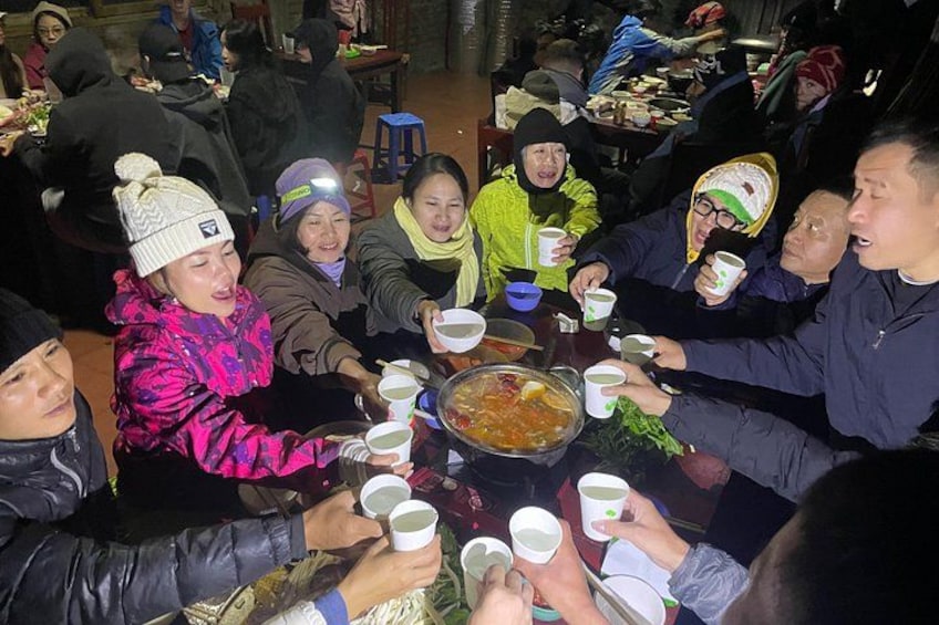 A group of people sitting around a table, holding cups, likely enjoying a meal or drink. 3