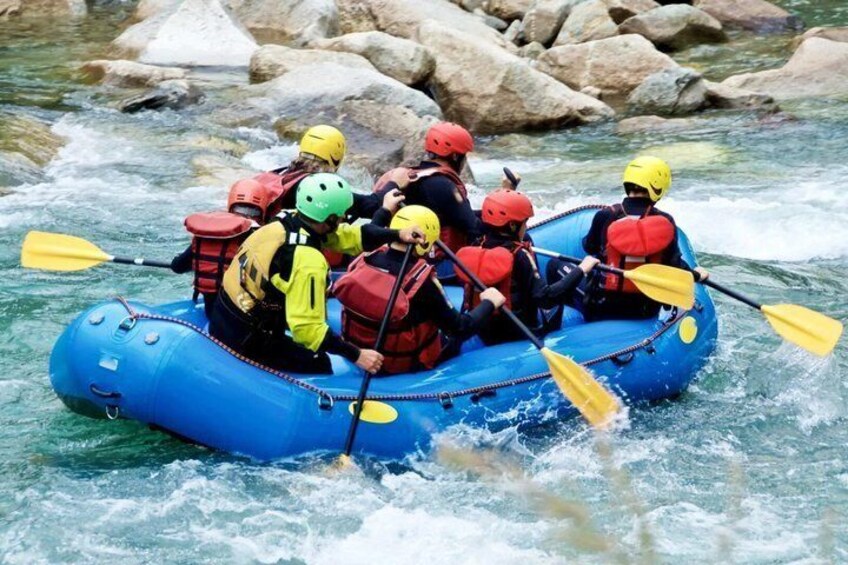Eine Gruppe von Menschen in einem blauen Luftboot durchfährt einen Fluss mit Stromschnellen. 5