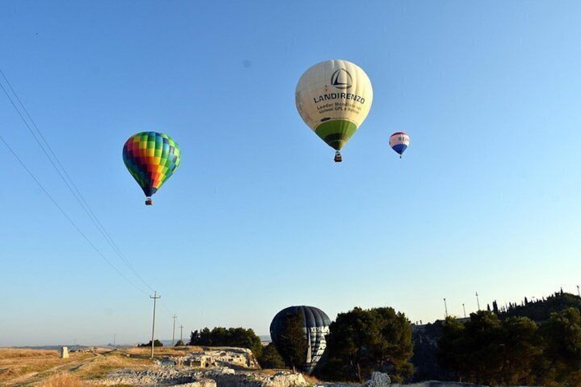 Three hot air balloons in the sky over a landscape with trees and power lines. 3