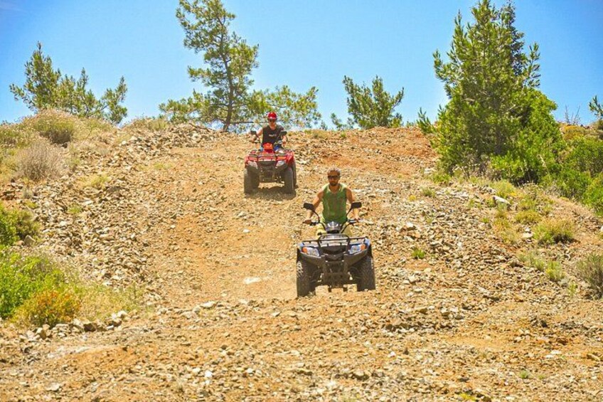 Dos personas conduciendo cuatrimotos por un terreno rocoso y montañoso con poca vegetación. 4