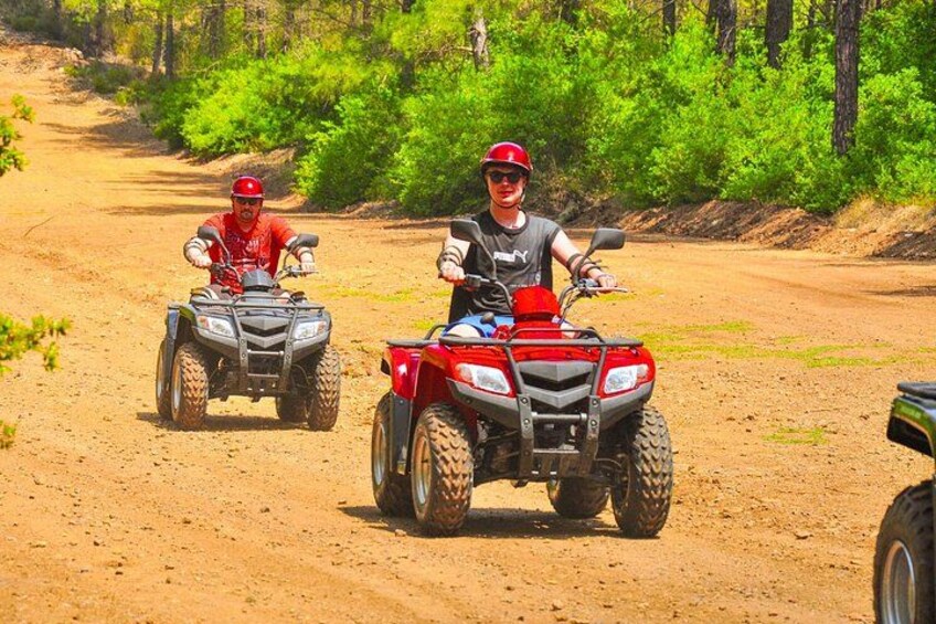 Dos personas conducen cuatrimotos rojas por un sendero de tierra rodeado de vegetación. 5