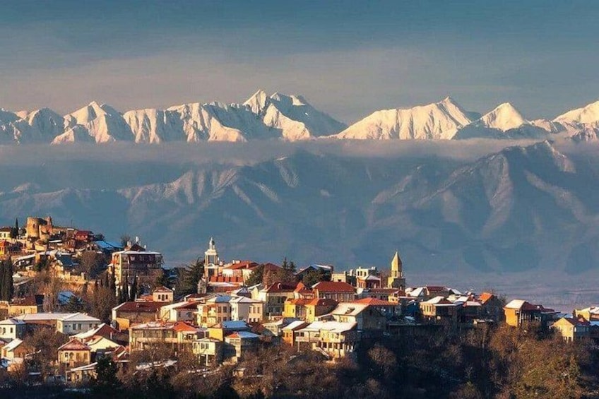A mountainous town with snow-capped peaks in the background and a mix of residential buildings in the foreground. 1