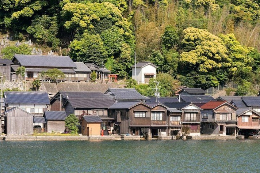 A traditional Japanese village by a lake with wooden houses and a hillside in the background. 3