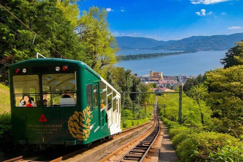A green train on tracks surrounded by lush greenery and a lake. 5