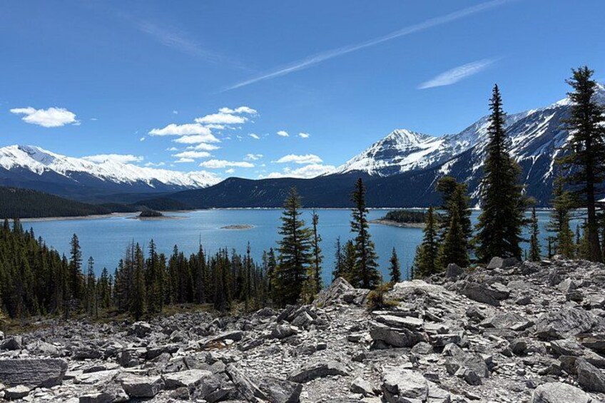 Eine Berglandschaft mit einem See, schneebedeckten Gipfeln und Nadelbäumen. 1