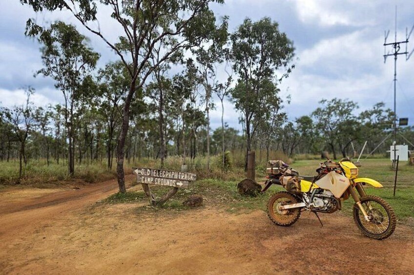 A dirt road, a sign for Old Telegraph Track Campgrounds, and a dirt bike. 5