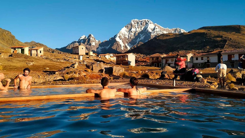 A group of people relaxing in a natural hot spring with mountains in the background. 3