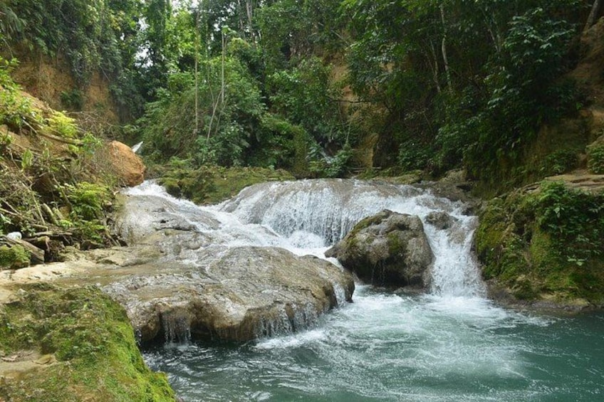 A waterfall cascading over rocks in a forested area. 2