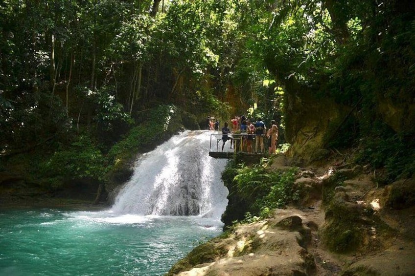 A waterfall with a viewing platform, surrounded by lush greenery. 4