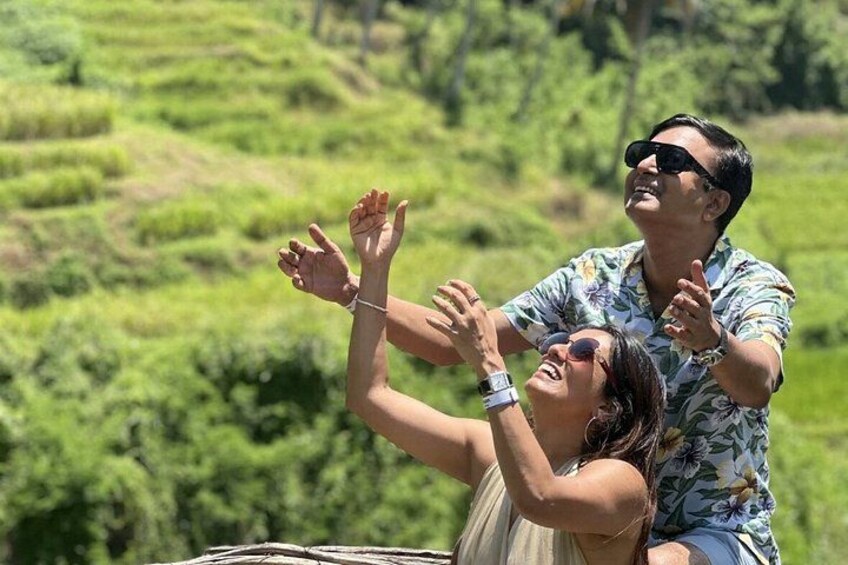 A person in a floral shirt and another in a beige dress, both raising their hands in a gesture. 3