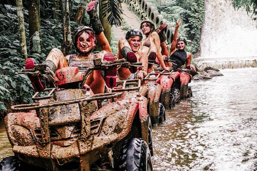 People on a muddy ATV in a forested area. 5