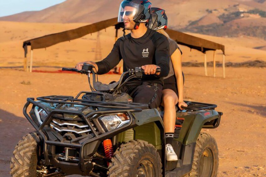 A person riding an ATV in a desert landscape with tents in the background. 4