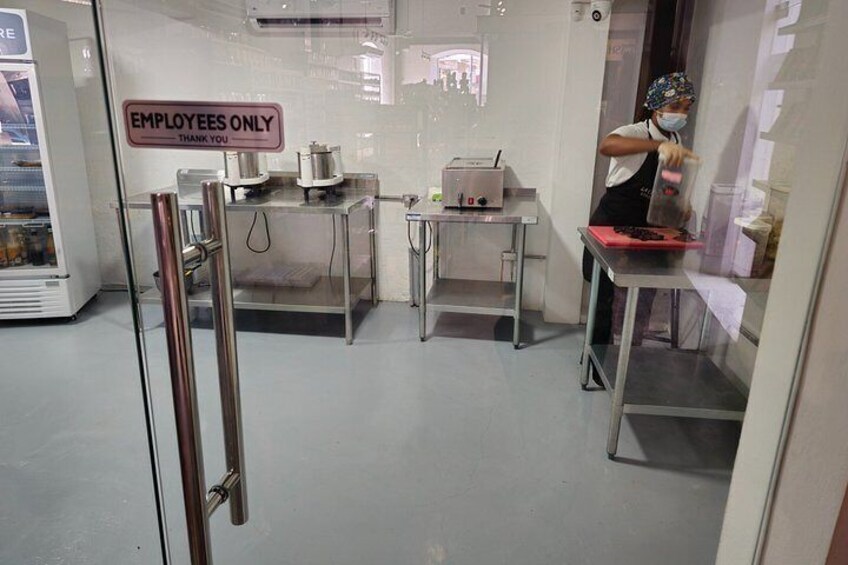 A kitchen area with a sign reading 'EMPLOYEES ONLY,' stainless steel counters, and a person working at a station. 5