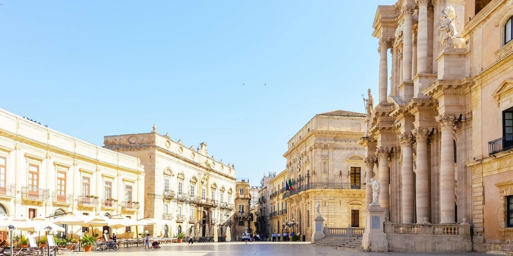 A historic square with ornate buildings, outdoor cafes, and a statue. 1