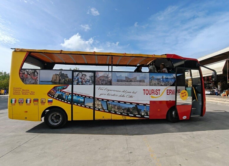 A yellow and red tourist bus with images of cities and landmarks on its side. 2