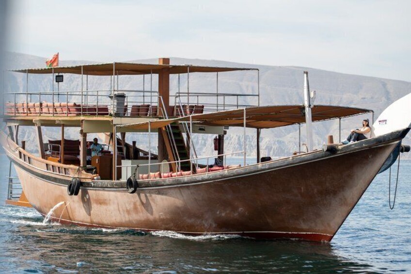 A wooden boat with a canopy, a person on the deck, and a mountainous landscape in the background. 3
