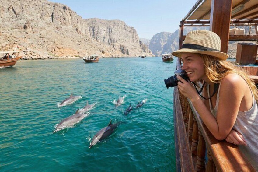A person taking a photo of dolphins swimming in the water. 1