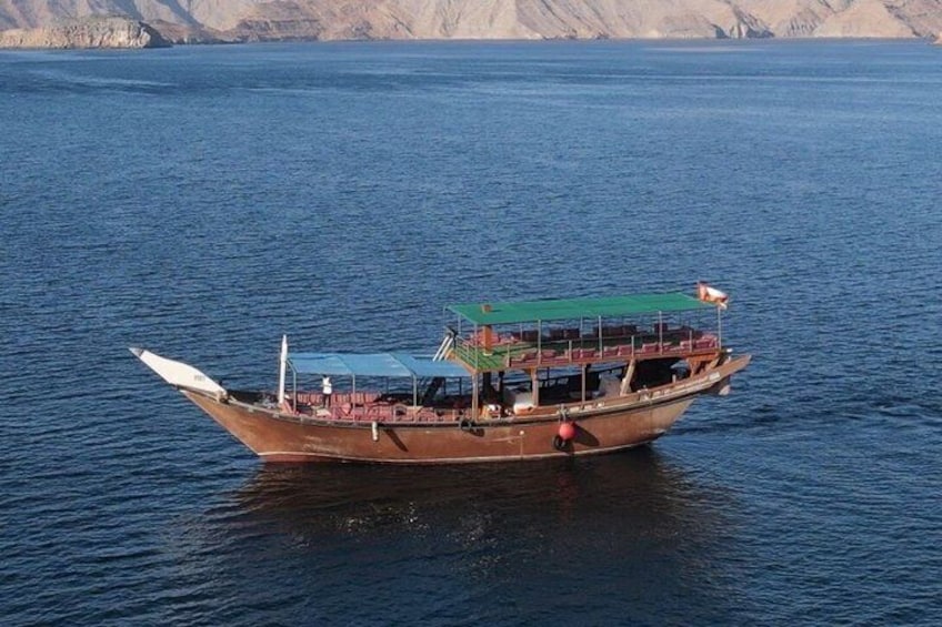A traditional wooden boat on calm water with a mountainous backdrop. 4