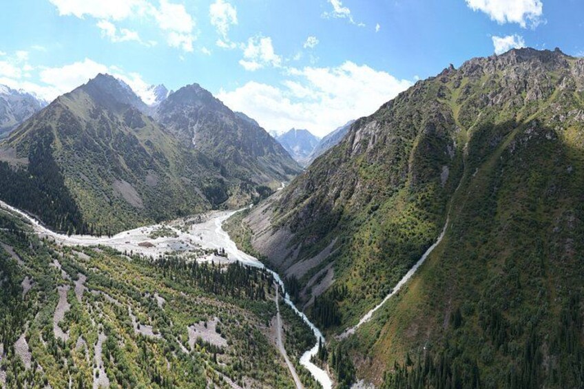Eine gebirgige Landschaft mit einem Fluss, dichten Wäldern und blauem Himmel. 3