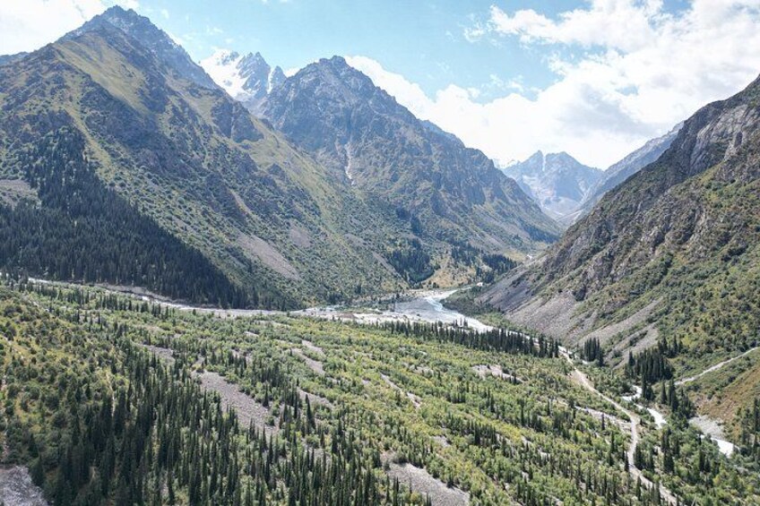 A mountainous landscape with a river, dense forests, and a clear sky. 2