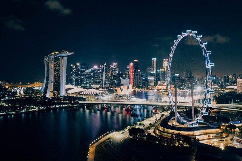A city skyline at night with prominent buildings including a tall tower and a large Ferris wheel. 2