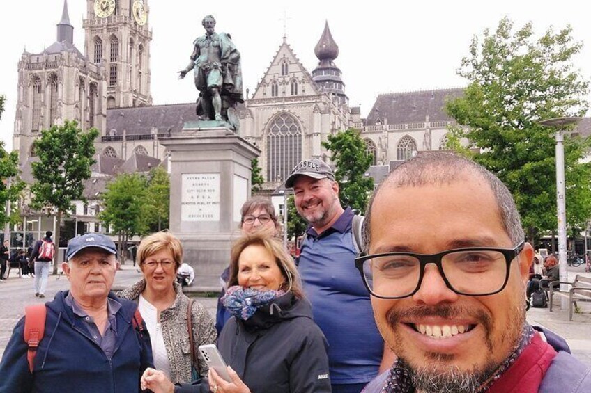 Un grupo de personas frente a un edificio histórico con una gran estatua y una torre de reloj. 4