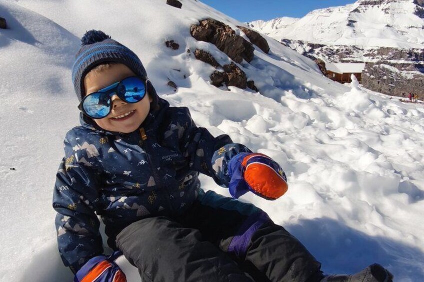 Un enfant assis dans la neige, avec une chaîne de montagnes en arrière-plan. 2