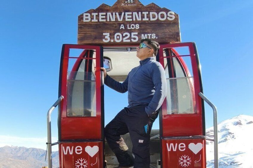 Une personne se tient à l’entrée d’un ascenseur rouge, sur lequel est affiché un panneau indiquant : « BIENVENIDOS A LOS 3 025 MTS. » 3