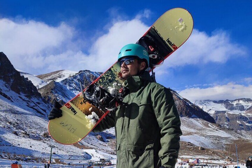 Une personne tenant une planche de snowboard, avec un paysage de montagne en arrière-plan. 1