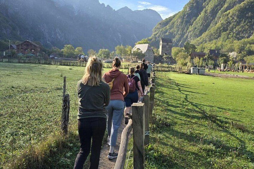 A group of people standing on a wooden fence overlooking a valley with a church and houses. 3