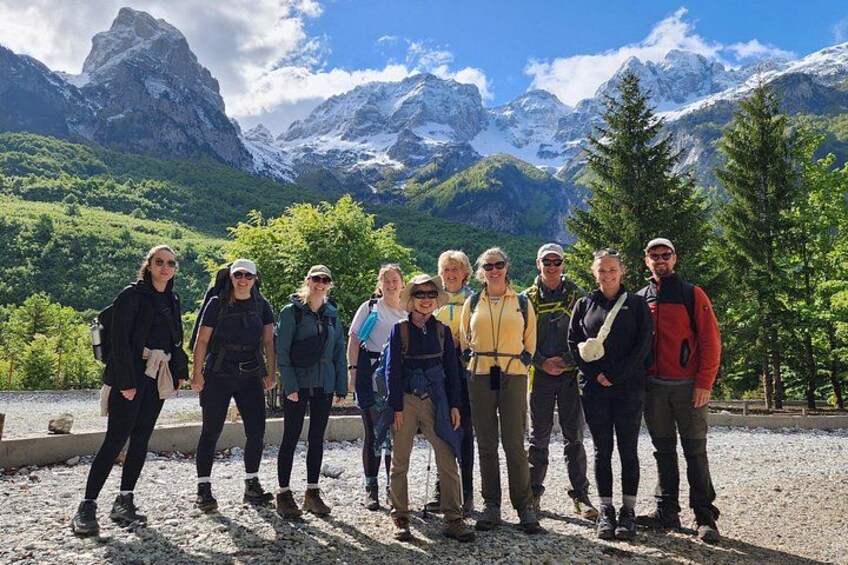 A group of people standing on a gravel path with a mountainous landscape in the background. 1