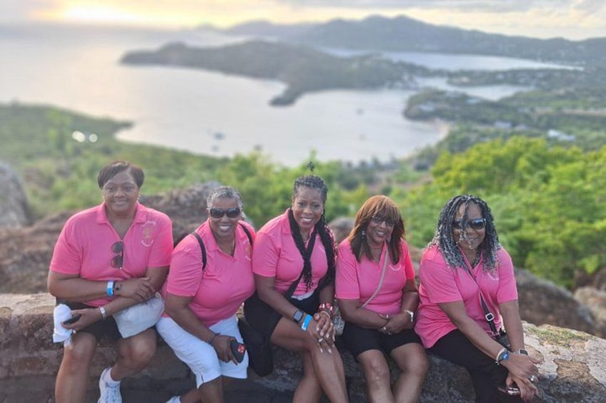 Un grupo de personas sentadas en un muro de piedra con vista a un cuerpo de agua y islas a lo lejos. 2