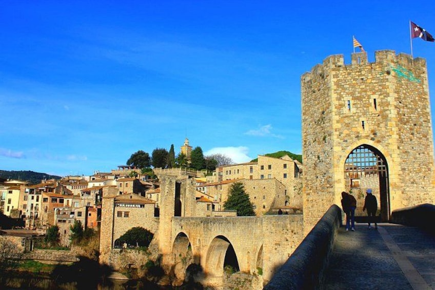 A historic stone tower, a bridge, and a town with buildings. 4