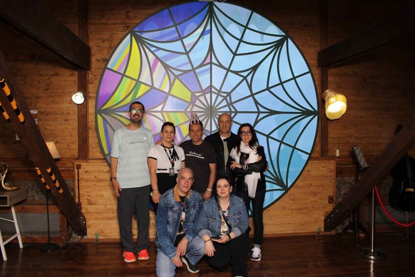A group of people posing in front of a large, colorful geometric wall art. 2