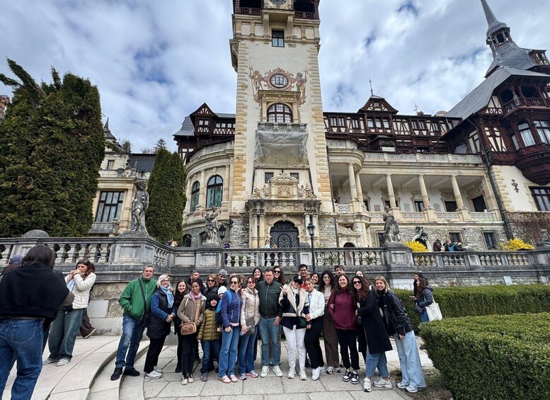 A group of people standing in front of a historic building with a clock tower and ornate architecture. 3